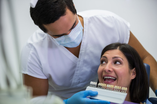 dentista-examina-paciente-femenino-tonos-dientes_107420-74149